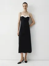 Vestido largo midi negro con breteles finos y escote recto con detalle blanco.