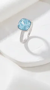 Anillo de plata con cristal cuadrado facetado en color celeste y engaste con circonias en el aro.