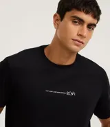 Remera negra de algodón, modelo comfort, con cuello redondo y manga corta. Presenta una pequeña estampa frontal en blanco con texto y un diseño minimalista de montañas.