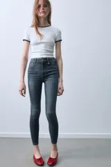 Jeans skinny de tiro alto en color negro, confeccionados en tejido super elástico de cinco bolsillos, con cierre frontal de cremallera y botón metálico.
