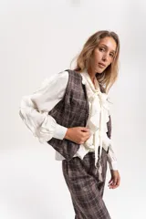 Chaleco sastrero de diseño italiano, con estampado a cuadros en tonos marrones y grises. Presenta escote en V, cierre frontal con botones y un corte entallado.