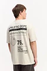 Remera oversize de color beige con gran estampado tipográfico y gráfico en la espalda de la marca Mistral.