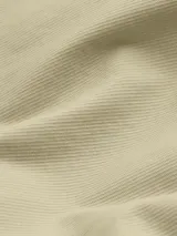 Camisa de manga larga color beige claro, con cierre frontal de botones, doble bolsillo en el pecho y logo pequeño en uno de los bolsillos.