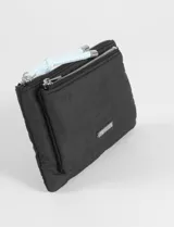 Monedero de tela color verde, con cierre superior y correa de muñeca estampada en azul y blanco. Presenta logo metálico en el frente.