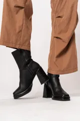 Bota de caña media color negro, de cuero, con horma cuadrada, taco geométrico con textura símil cocodrilo y plataforma.