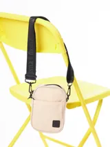 Bandolera color crudo con correa negra ajustable con el logo de la marca.