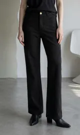 Pantalon de gamuza color marron, de corte recto y tiro medio, con cierre frontal y bolsillos laterales.