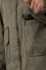 Chaqueta de estilo militar color verde oliva, confeccionada en gabardina resistente. Presenta cuello camisero en contraste color negro, cierre frontal con cremallera, dos bolsillos frontales tipo cargo con solapa y ajuste relajado.