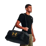 Bolso deportivo Under Armour Undeniable 5.0, color negro con logo de la marca en color dorado. Cuenta con correa ajustable para el hombro y asas de mano, ideal para transportar equipamiento deportivo.