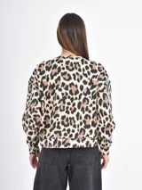 Buzo de cuello redondo y manga larga con estampado animal print de leopardo en tonos beige, marrón y negro. Presenta un corte holgado y puños y ruedo acanalados.