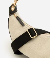 Cartera tipo shoulder de diseño curvo y estructura mediana, confeccionada en tejido texturizado con detalles en material sintético negro. Cuenta con cierre superior y correa ajustable y desmontable.