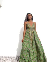 Vestido largo de estilo bohemio en color verde, con estampado paisley, escote en V profundo y breteles finos. Presenta detalles bordados con pedrería y espejos a lo largo del escote y el centro del frente, con una falda amplia y fluida.
