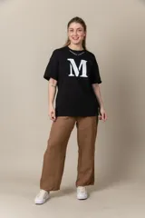 Remera gris con estampa de la letra M en negro y cadena plateada en el cuello.