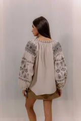 Blusa blanca con bordados en contraste de estilo bohemio, mangas amplias y diseño ligero.