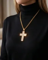 Collar de acero con baño de oro, compuesto por una cadena de eslabones y un dije en forma de cruz con incrustaciones de cristales brillantes.