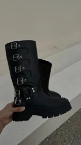 Botas de cuero negras de caña alta con hebillas plateadas y suela track.