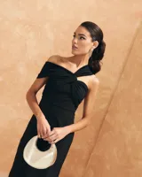 Vestido largo negro con escote bardot, detalle de nudo en la parte delantera y abertura lateral.