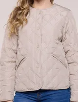 Campera matelaseada color verde militar con diseño capitoneado de rombos, escote redondo sin cuello y cierre frontal con broches a presión. Cuenta con bolsillos frontales oblicuos y ruedo curvo con aberturas laterales.
