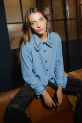 Camisa celeste de jean 100% algodón con voladitos y bordado de onditas en el cuello y puños.