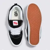 Championes Vans modelo Knu Skool inspirados en los años 90, con diseño de perfil bajo, parte superior de gamuza resistente en color negro, lengüeta y cuello acolchados abultados, y suela de goma blanca con la característica franja lateral Sidestripe en relieve.