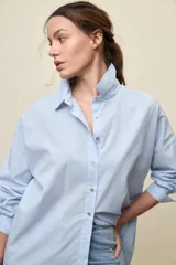 Camisa celeste de corte oversize, con mangas largas, cuello camisero y cierre frontal de botones.