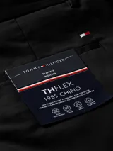 Pantalón chino negro de corte slim con pierna recta, confeccionado en algodón pima elástico. Presenta cierre de cremallera con botón, dos bolsillos ribeteados en la cintura y dos bolsillos traseros de ojal con botón.