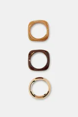 Pack de tres pulseras rígidas de diseño minimalista. Incluye dos brazaletes de resina con efecto carey en tonos marrón claro y oscuro, y un brazalete metálico de acabado dorado.