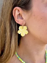 Aros colgantes compuestos por una argolla pequeña de acero quirúrgico dorada y un dije en forma de flor de color amarillo con acabado pintado a mano.
