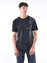 Remera de corte oversized en color negro con un panel lateral en gris oscuro y bolsillo frontal con el logo de la marca estampado.
