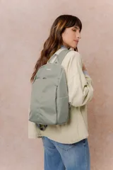 Mochila color verde militar con diseño minimalista y compacto. Cuenta con compartimento principal con cierre, bolsillo frontal con cierre oculto, bolsillos laterales y correas regulables y acolchonadas. Incluye logo metálico de la marca en el frente.