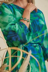 Pulsera de cadena dorada con cinco dijes circulares de piedra verde esmeralda facetada.