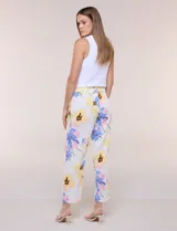 Pantalón ankle de sastrería color blanco con estampado floral multicolor, de corte recto y tiro medio con cordón de ajuste en la cintura.