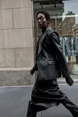 Blazer entallada de cuello solapa y manga larga con hombreras, confeccionada en efecto piel color negro. Cuenta con bolsillos delanteros con solapa y cierre frontal cruzado con botones.