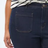 Pantalón de jean corte flare en color azul oscuro, con cintura alta y bolsillos frontales tipo parche.