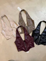 Top beige de cuero sintético con cuello halter y cierre frontal con cremallera.