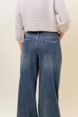 Jean wide leg de tiro alto con costura frontal decorativa, bolsillos delanteros con remaches y bolsillos traseros amplios. Presenta un interior afelpado para mayor abrigo.