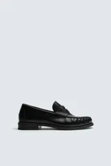 Mocasín de vestir fabricado en piel color negro, con detalle de antifaz en el empeine y suela a tono con ligero tacón.