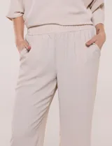 Pantalón pull-on de color beige con caída fluida, cintura elastizada fruncida, bolsillos laterales funcionales y pierna amplia de corte wide leg.