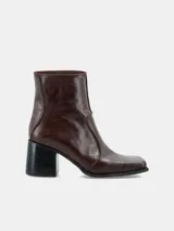 Bota de caña media confeccionada en cuero, con diseño de punta cuadrada y taco bloque de altura media.