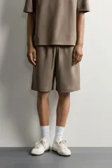 Bermuda estilo jogger de ajuste relajado, confeccionada en tejido interlock de algodón. Cuenta con cintura elástica ajustable con cordón, bolsillos frontales de vivo y diseño liso.