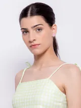 Top corto con escote recto y tirantes finos ajustables mediante nudo en los hombros. Presenta un estampado floral sobre fondo oscuro, con flores rosadas y hojas turquesas.