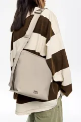 Bolso bandolera de tamaño pequeño, confeccionado en poliamida con detalles en piel vacuna. Cuenta con asa regulable de tejido, cierre con cremallera, bolsillo interior y logo de la marca estampado en la parte frontal.