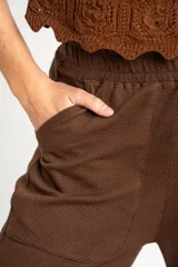 Pantalón de corte recto y tiro medio, confeccionado en tejido de algodón con textura tipo waffle. Cuenta con cintura elástica y bolsillos laterales.