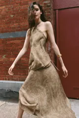 Falda midi de tiro alto y diseño asimétrico con cierre frontal cruzado y botón decorativo. Presenta una textura rústica con estampado sutil y forro interior marrón.