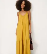 Vestido largo mostaza de viscolino con escote en U, breteles finos y corte evasé con caída fluida. Cuenta con un recorte fruncido en el ruedo.