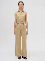 Mono largo de denim azul con corte holgado, recto en las piernas y entallado en el tronco. Tiene cuello camisero, cierre frontal con cremallera y cinturón ajustable.