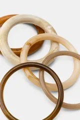 Pack de cinco pulseras rígidas de resina en tonos marrones, beige y tostados, con diseño liso y acabado brillante.