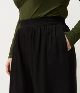 Pantalón de corte aladín confeccionado en crepé, de tiro alto con cintura elástica en la parte trasera. Presenta piernas anchas con volumen tipo globo que se estrechan en los tobillos mediante puños elásticos. Incluye bolsillos laterales funcionales.
