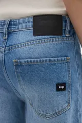 Jean de tiro medio con diseño barrel, de pierna amplia y curvada que se estrecha sutilmente hacia el ruedo, en tono azul clásico con efecto desteñido.