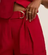 Short de vestir rojo de cintura alta, con cinto de hebillas media luna dobles en la cintura, pliegues y bajo plegado.